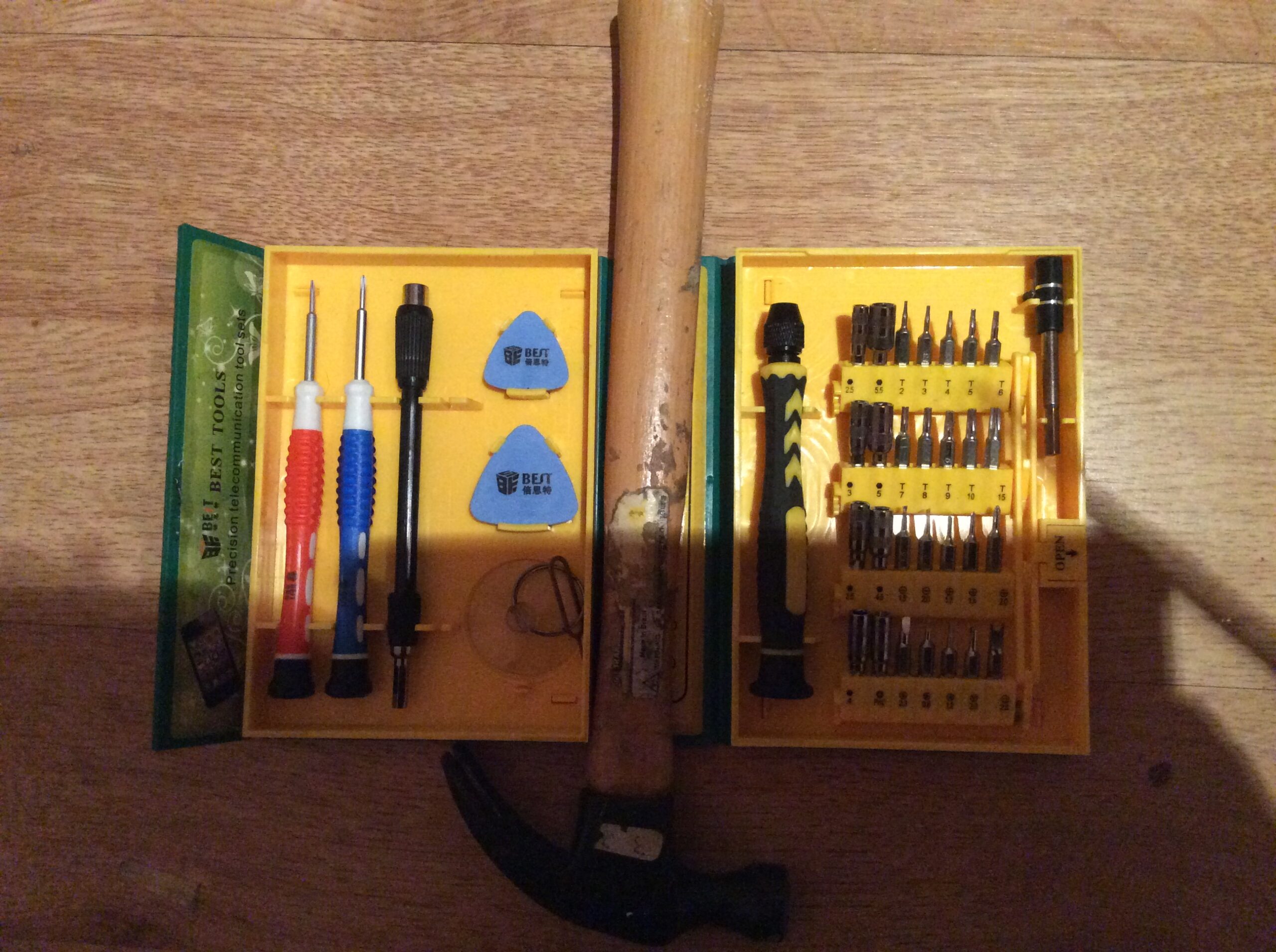  A photograph of my yellow toolbox  with a shadow cast over it and a hammer on a laminated wooden floor