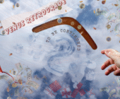A hand in the cloudy sky throws a dark wooden boomerang, a kite glades through and a plane with a banner reads Venus retrograde. Dollar notes , coins, and wrapped gift parcels fall from the sky.