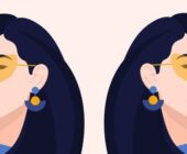 A coloured illustration of a side profile of two identical women on either side of one another, both have their dark hair down swooped to the left and right side, wearing identical yellow shades a blue sweater and you can see one blue drop-down earring with a yellow circle on each woman to represent How to spot a Gemini woman