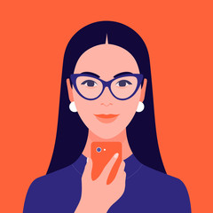 A woman with dark hair and a small center parting wearing indigo glasses and white earrings, indigo turtleneck holds a orange cell phone the matched the colour of the background. The woman depicts how to spot an Aries woman