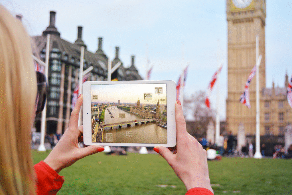 A photoshopped potography iPad Mini in the hands of a woman outdoors the house of Parliment the image in the ipad is of another side of Parliment near the river with captions of where I was born